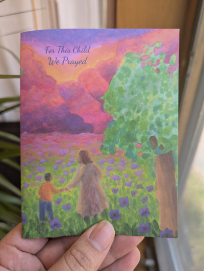 Christian baby dedication card with an original painting of Jesus holding a young child's hand, walking through a field of purple flowers toward a colorful sunset sky; cover reads "For This Child We Prayed"